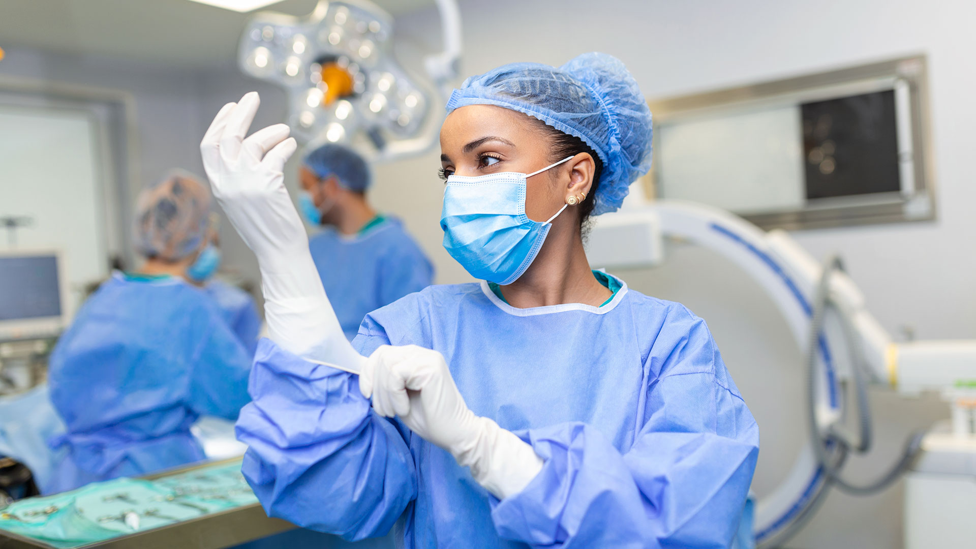 Médica coloca as luvas cirúrgicas enquanto se prepara para a cirurgia
